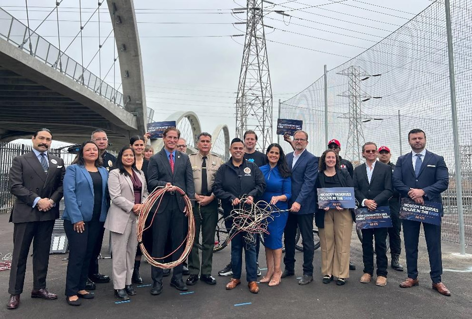 Group photo of Asm. González, guest speakers and attendees, with bridge in background