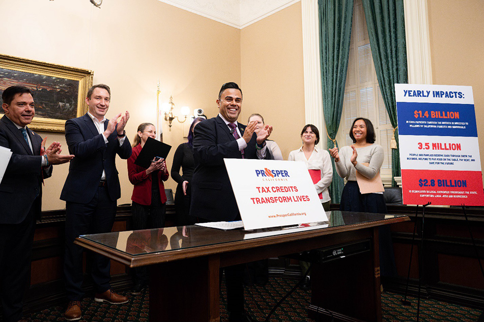 Asm. González and others standing and clapping, with large signs on display