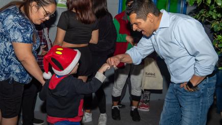 Assemblymember Santiago fist-bumping a small child