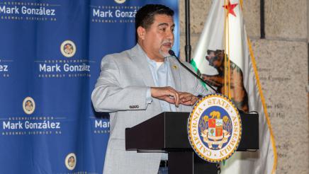 Guest speaker at podium, speaking and gesturing with both hands