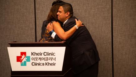 Asm. González hugging speaker at podium