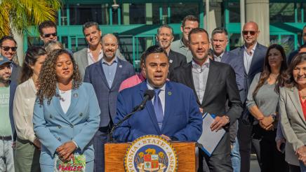Asm. González at podium, speaking