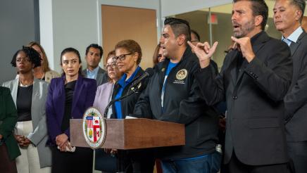 Asm. González as podium, speaking, as Mayor Bass, Speaker Rivas and others listen on