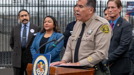LA County Sheriff at podium, speaking, as others listen on