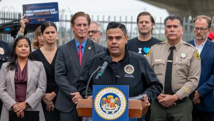 Asm. González at podium, speaking, as others listen on