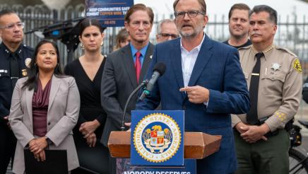 Guest speaker at podium, speaking, as others listen on