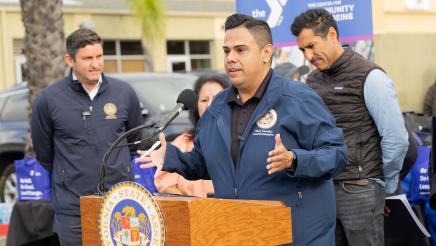 Asm. González at podium, speaking, as Speaker Rivas and others listen on