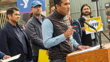 Speaker Rivas at podium, speaking, as supporters on