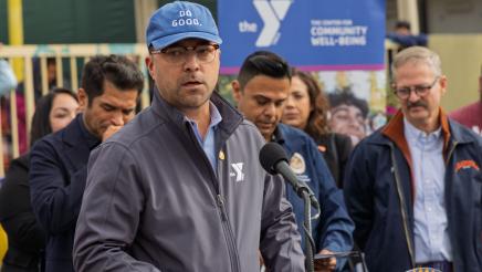 Guest speaker at podium, speaking, as supporters on