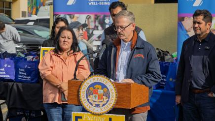 Guest speaker at podium, speaking, as supporters on